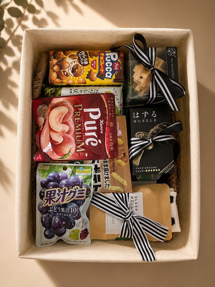 A gift basket of Japanese snacks and puzzles, each tied with black and white striped ribbon