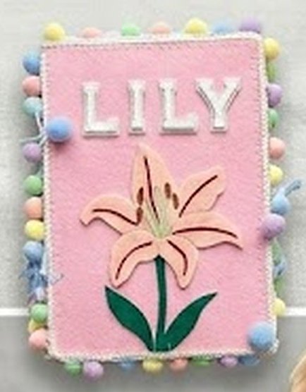 A felt busy book cover with the name Lily stitched above a felt lily flower